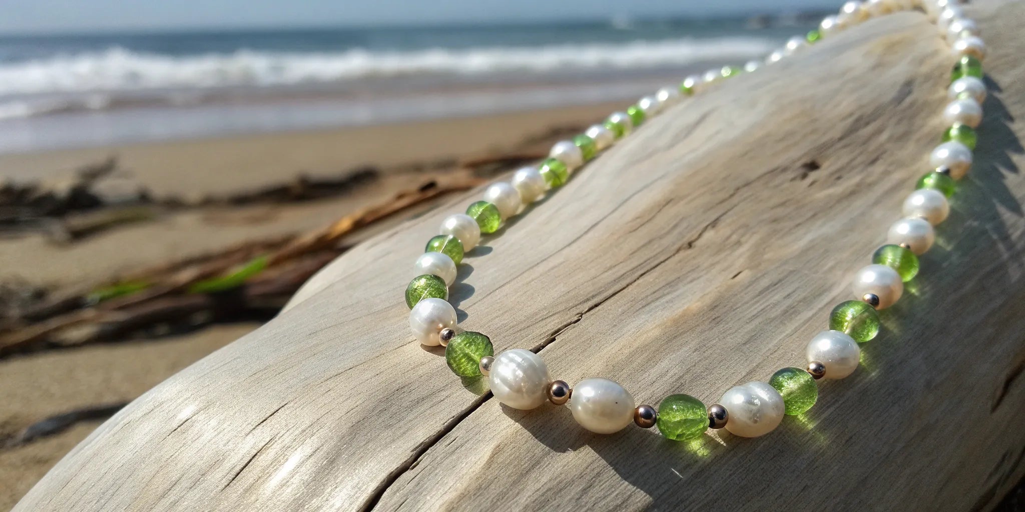 A bohemian peridot and pearl necklace on a piece of driftwood.