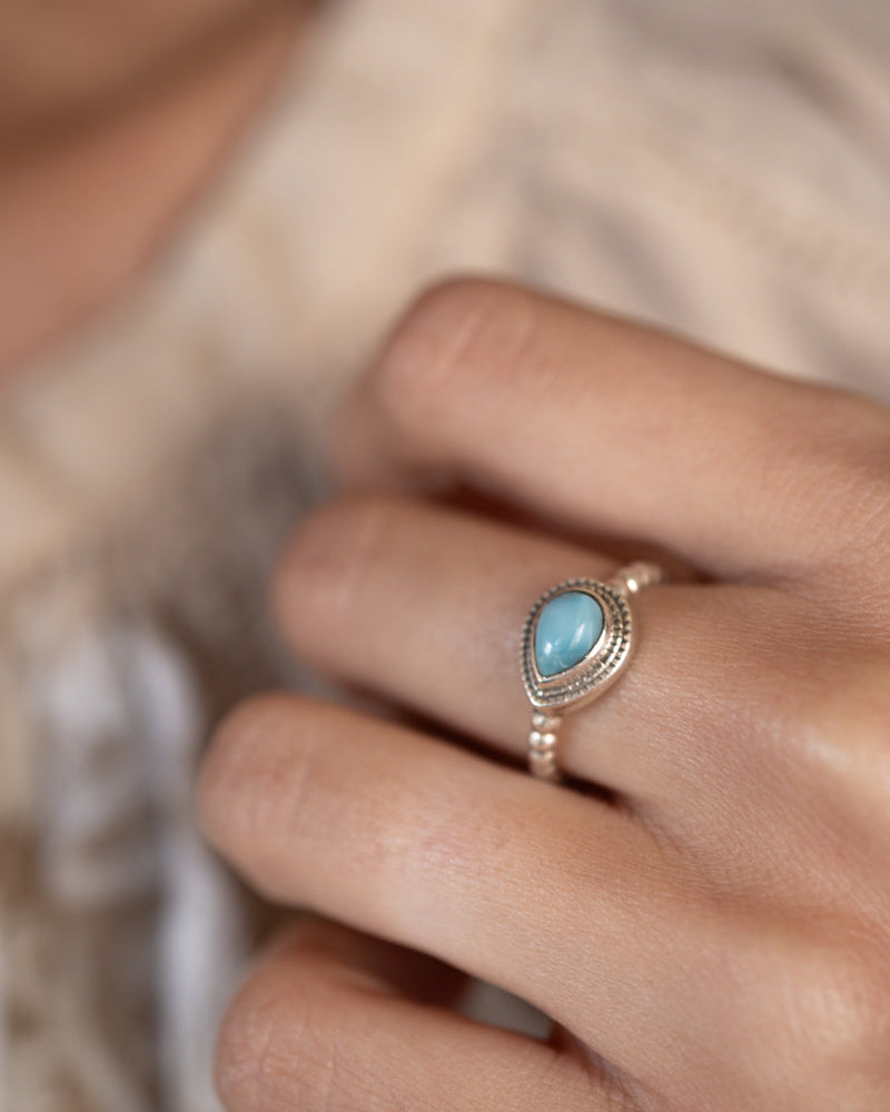 Close-up of a hand wearing a larimar
ring with a blurred background