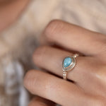 Close-up of a hand wearing a larimar
ring with a blurred background