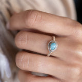 Close-up of a hand wearing a ring with a blue larimar 
gemstone.