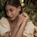 Woman adjusting her turquoise climber earrings with a natural background